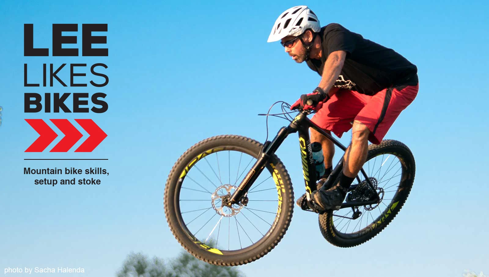 A mountain biker airborne against a clear blue sky (photo by Sacha Halenda)
